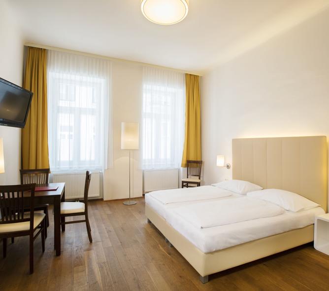 Schlafzimmer in den Hahn Studios mit Doppelbett, großer Fensterfront, Flatscreen und Tisch mit Stühlen